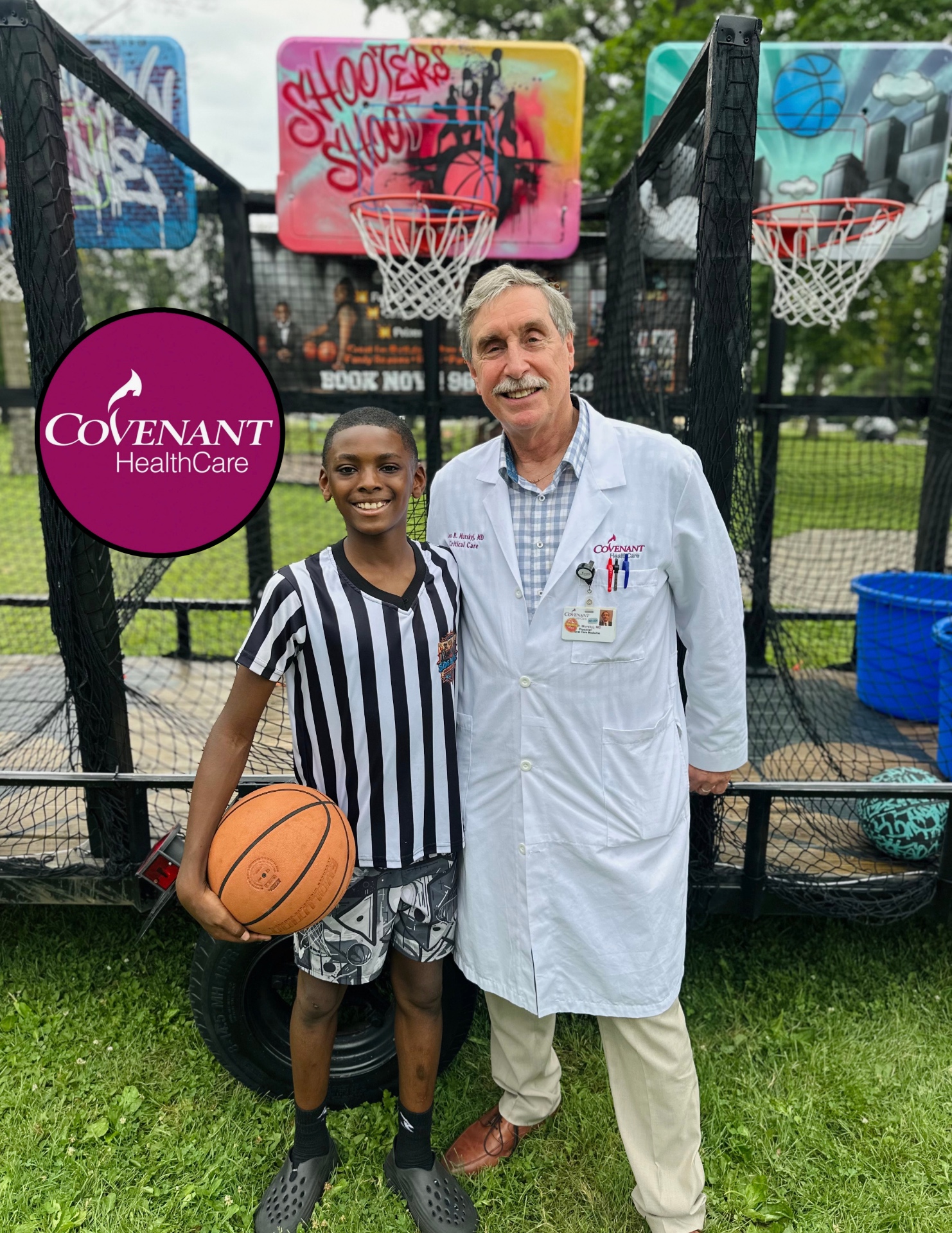 A young Side By Side team member holding a basketball beside a Covenant HealthCare physician at a community health event.
