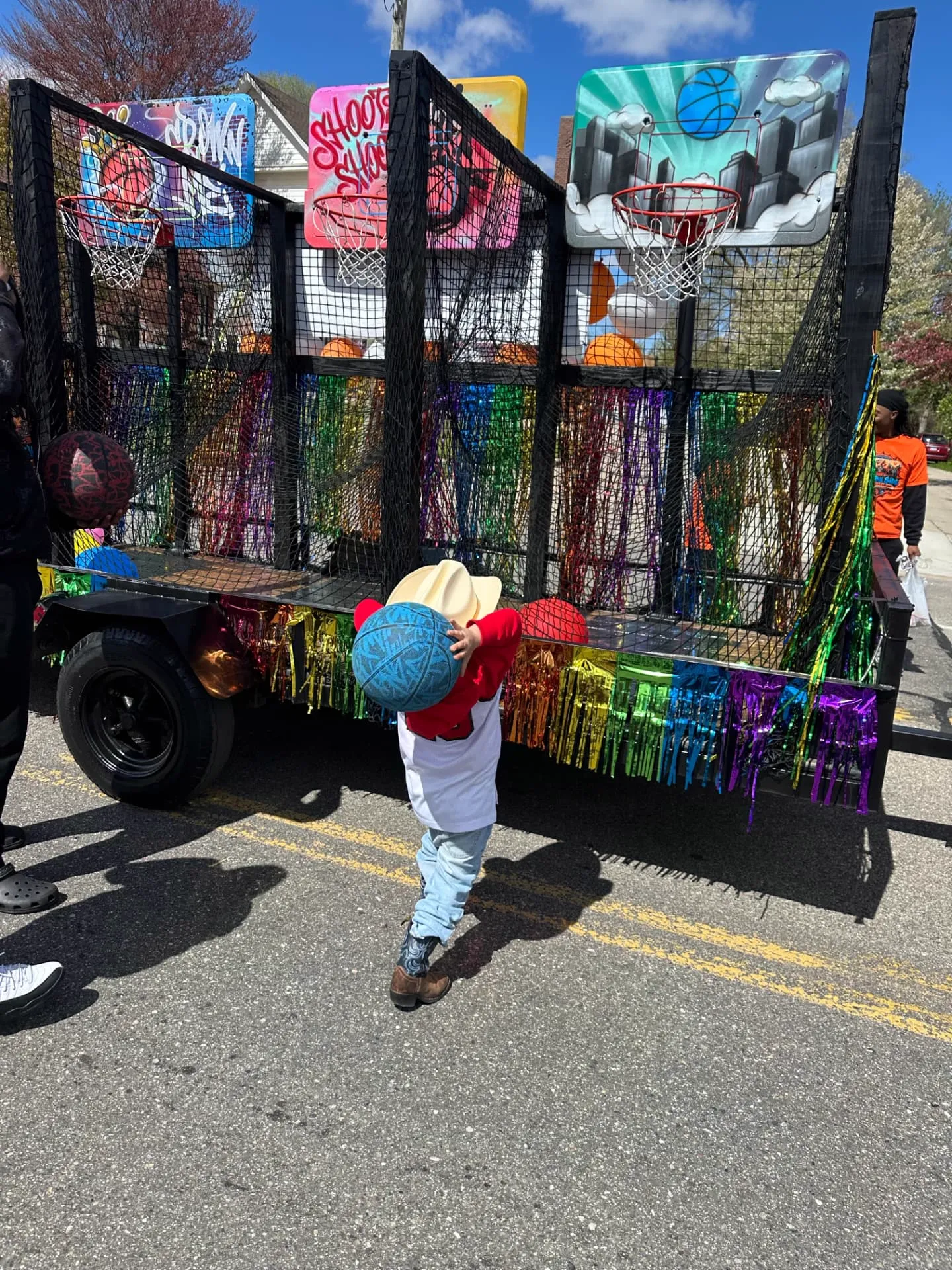 The full side of the Side By Side Mobile Hoops trailer, showing four hand-airbrushed graffiti backboards, red rims, and safety netting.