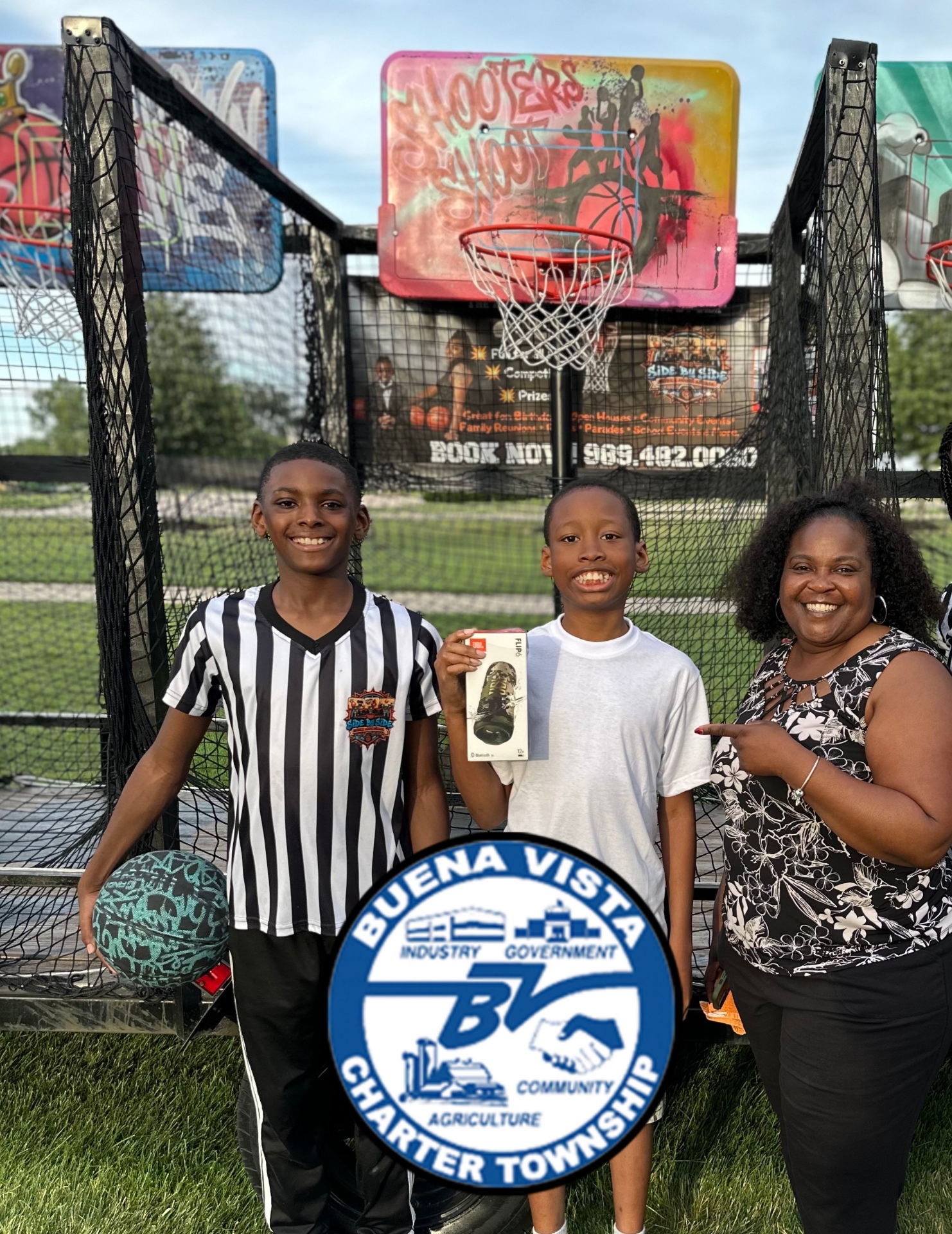 A prize winner holding a speaker with the Side By Side crew at a Buena Vista Charter Township community event.