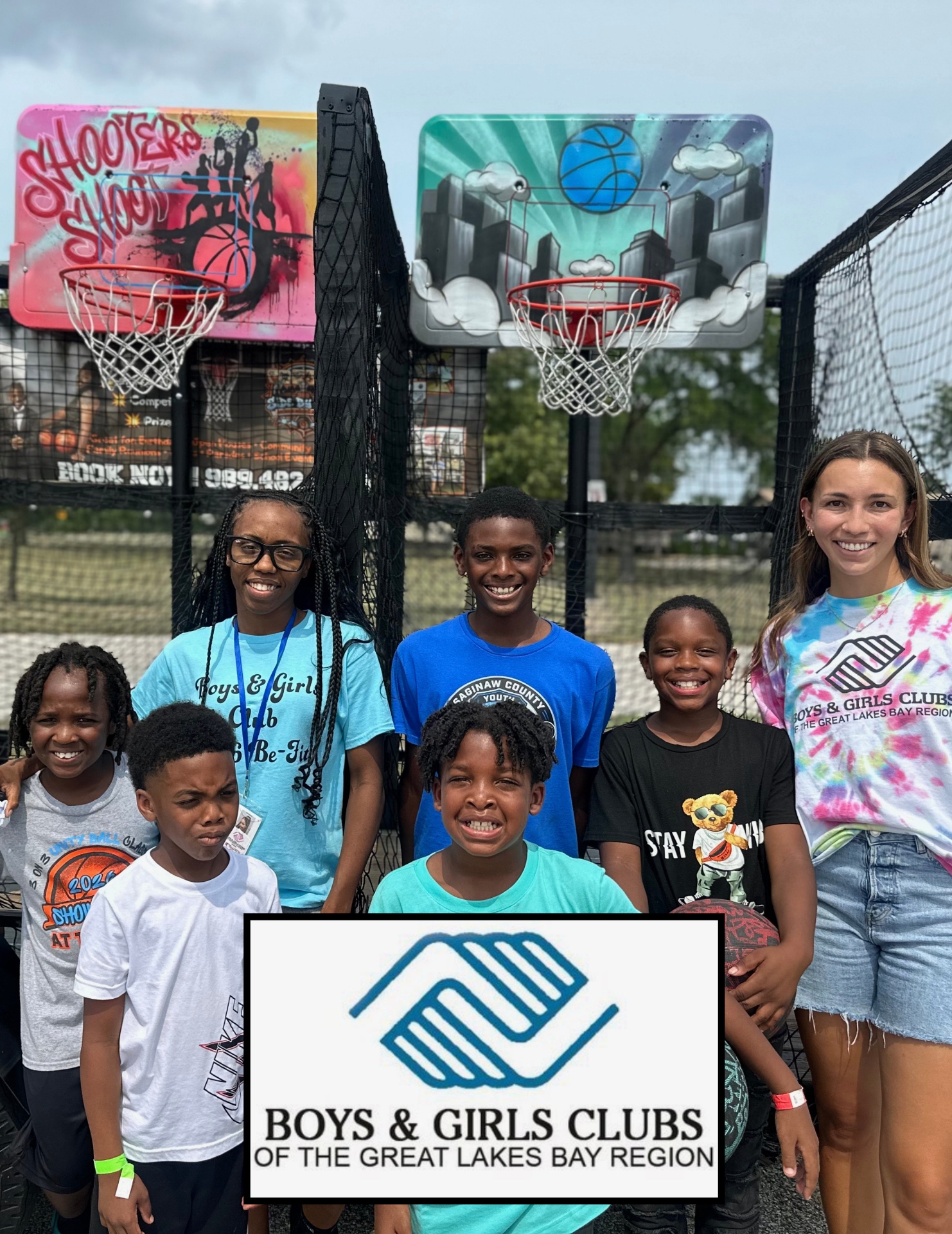 A group of kids and a staff member from the Boys & Girls Clubs of the Great Lakes Bay Region in front of the hoops trailer.