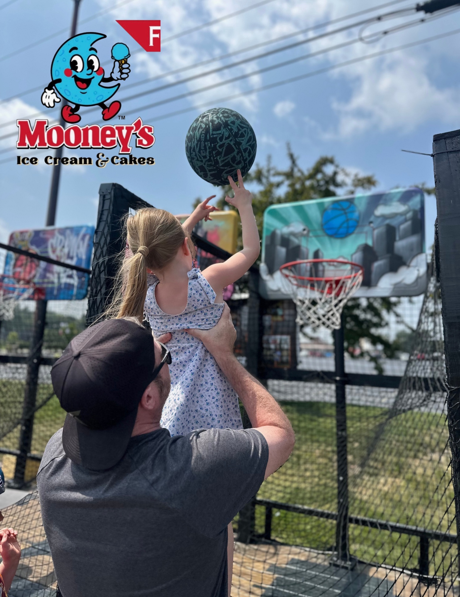 A dad lifting his daughter up to shoot at the trailer during an event at Mooney's Ice Cream & Cakes.