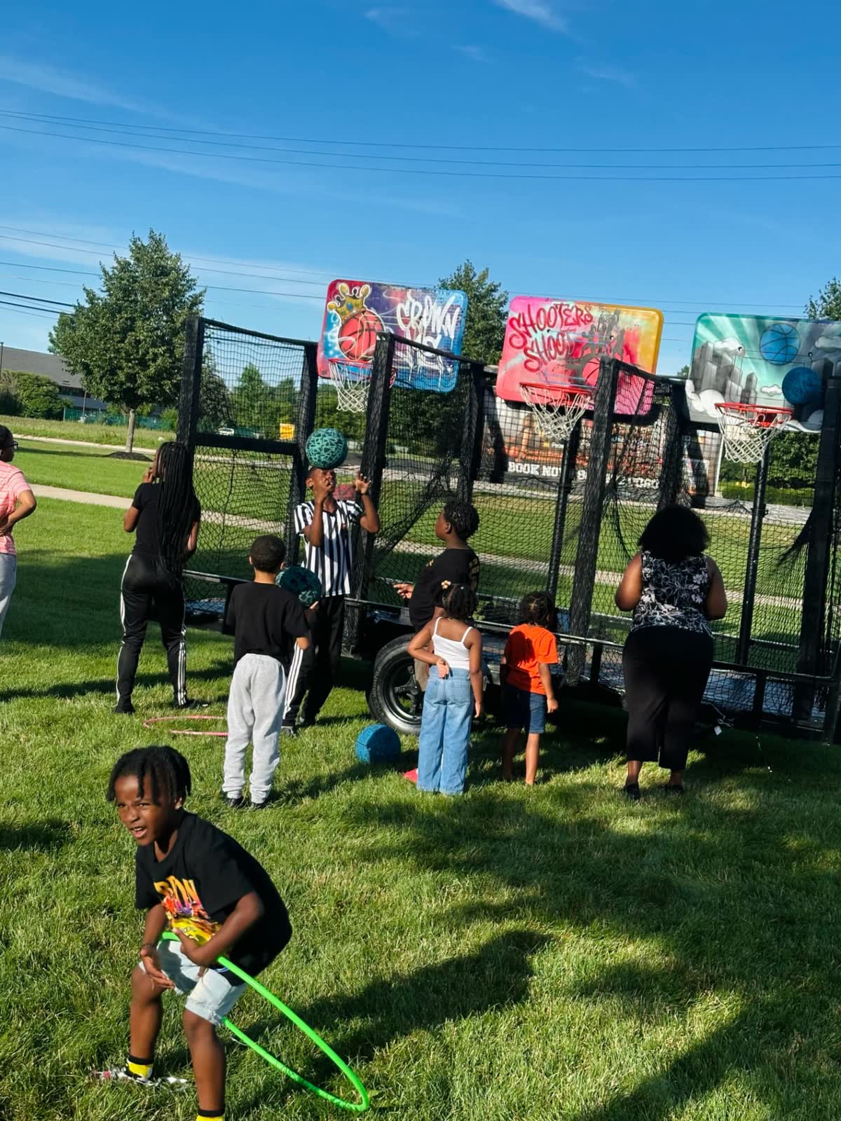 Children and parents gathered along the hoops trailer on the grass, waiting for their shot.